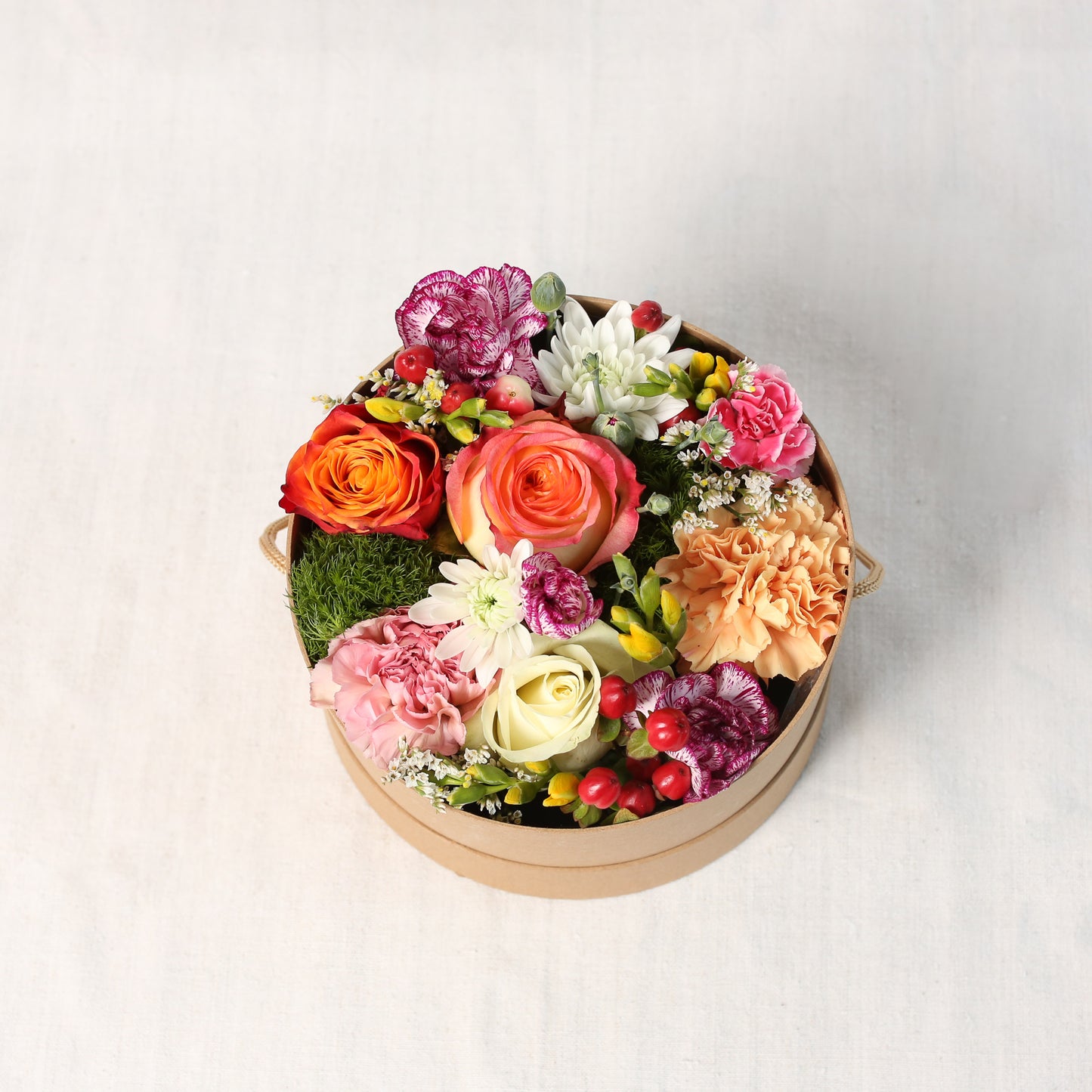 Draufsicht - Bunt gemischte Saisonblumen, gesteckt in einem naturfarbenen Rundkarton.