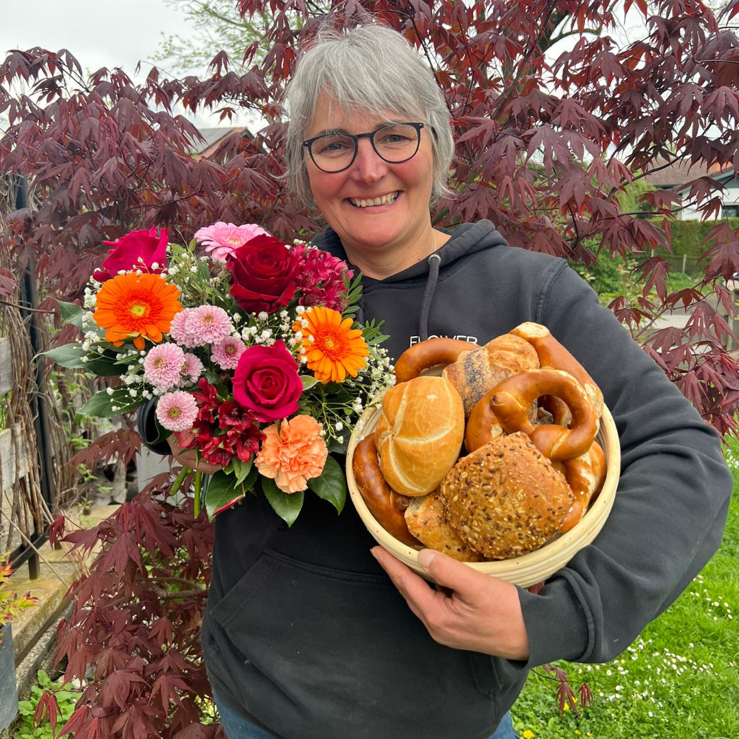 Heidi Pütz vom Blumengeschäft Flower Power aus Rosenheim mit einem bunten Sommerstraß und einem Brotkorb mit Semmeln und Brezeln