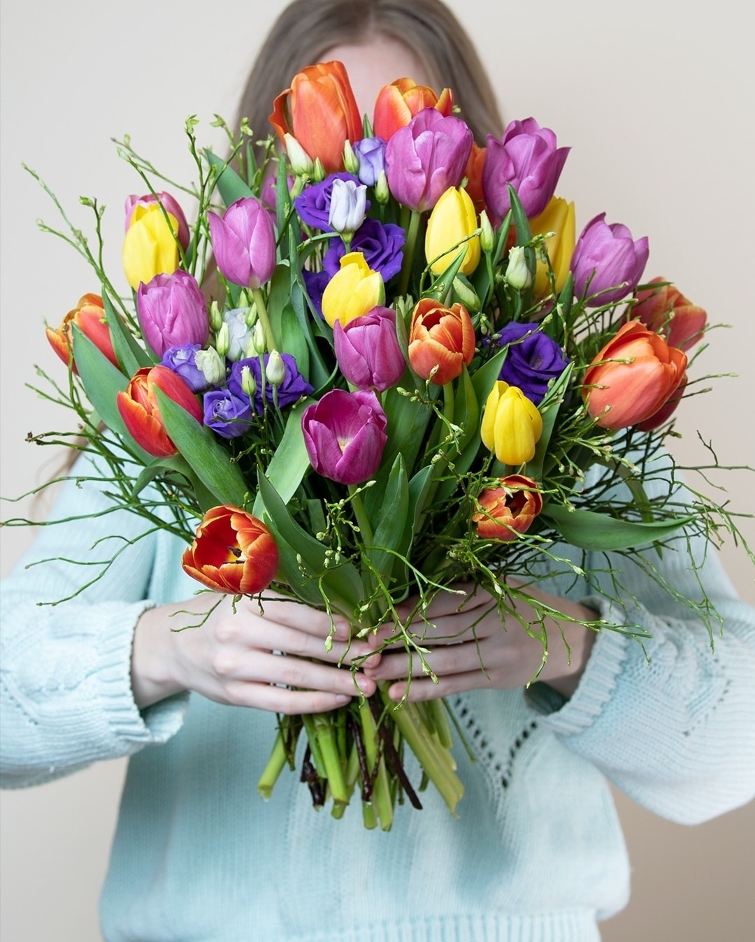 Bunter Tulpenstrauß in Größe L mit Heidelbeere. Präsentiert von einer Person