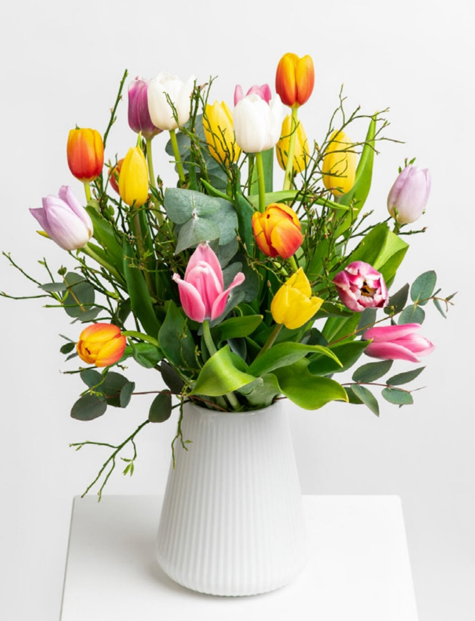 Bunter Tulpenstrauß in Größe S mit Heidelbeere in einer weißen Vase. Vase im Lieferumfang nicht enthalten