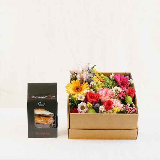 Bunte Blumenvielfalt, gesteckt in einem braunen, quadratischen Karton mit Deckel und dazu unsere feinen Florentiner (150 g) aus dem Vorarlberg